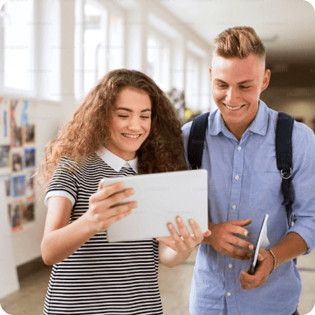 Two people looking at the screen smiling in a building hallway